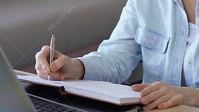 Business woman writing down to notebook plan for near future, making schedule