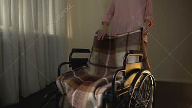 Woman taking away empty wheelchair, thinking about mother, sorrow for beloved