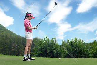 Asian woman golf player doing golf swing tee off on the green sunset evening time,