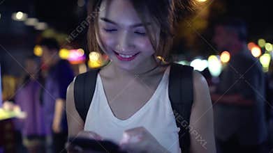 Slow motion - Asian woman tourist backpacker smiling and using smartphone traveling alone holidays outdoors on city street.