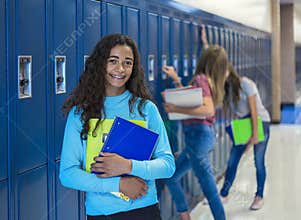 Junior High school Student standing by her locker in a school hallway