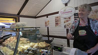 Old lady in bakery shop is happily serving customer [flat profile]