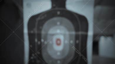 A silhouette target at a gun range slides towards the camera - dark cinematic version