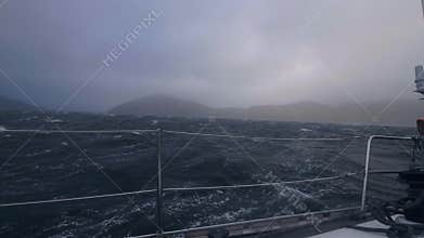 View from board yacht sailing on stormy sea waves. Sail boat swinging on waves