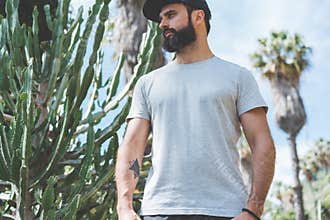 Bearded muscular hipster man model wearing gray blank t-shirt and a black baseball cap with space for your logo or