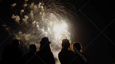 A crowd of people watch colorful fireworks and celebrate.
