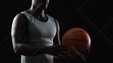 Tall black athlete carrying basket ball in hands, thinking about game strategy