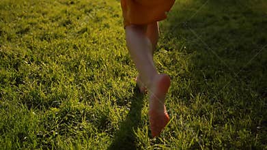 Young attractive woman feet running by grass in park, barefoot.