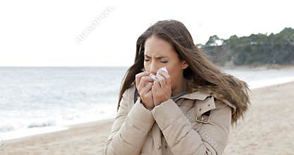 Ill woman coughing in a cold day on the beach