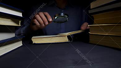 Man using magnifying glass for reading the book. Investigation and developing.