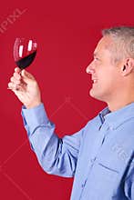 Man checking a glass of red wine for clarity