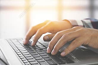 Man hands typing on a laptop keyboard on a desk