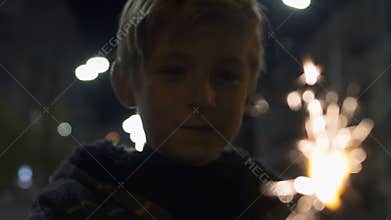 Happy boy holding lit firework sparkle at Christmas eve, celebration with family