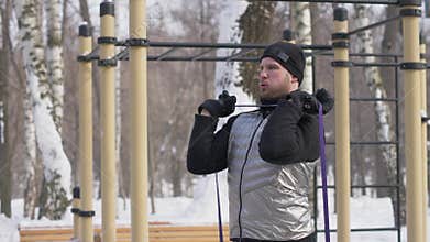 Handsome man doing workout exercise with fitness expander on sports ground