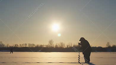 Fisherman drills a hole ice fishing