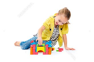 Young girl building a castle with wooden toy block. Child play therapy concept on white background.