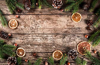 Creative layout frame made of Christmas fir branches, spruce, slices of orange, pine cones, snowflakes on wooden background
