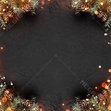 Creative layout frame made of Christmas Fir branches with pine cones on dark holiday background with light.