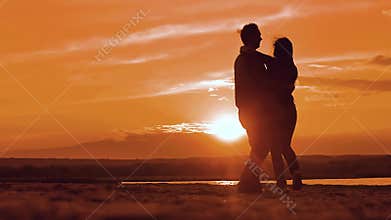 Silhouette man and girl of a happy young married couple slow dancing outside at sunset. Couple enjoying on nature the