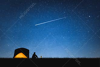 Silhouette of traveler camping on the mountain and night sky with stars. Space background.