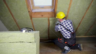 Man installing thermal roof insulation layer - using mineral woo