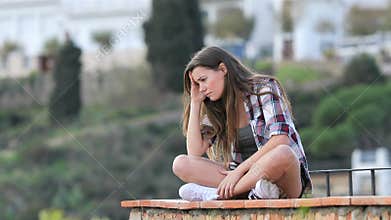 Sad teenage girl complaining sitting on a ledge