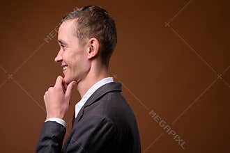 Studio shot of young businessman against brown background