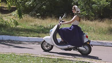 Young beautiful pin-up woman on the street with electric scooter