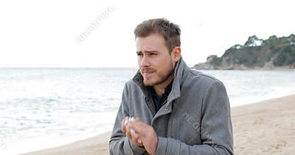 Ill man coughing in a cold day on the beach