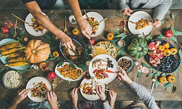 Flat-lay of friends feasting at Thanksgiving Day table with turkey