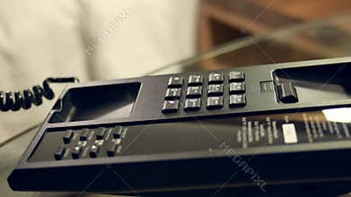 Closeup businessman hand making 911 call on telephone