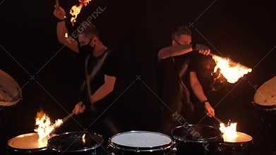 Two young men playing fire drum.