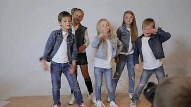 Photographer taking pictures of happy children posing in photo studio.