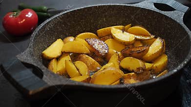 Home cooking background. Fatty food. Appetizing rustic yellow unpeeled potatoes cooked with olive oil fried in a pan