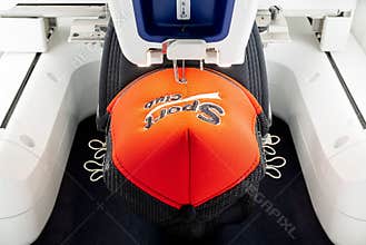 Red and black sport cap on embroidery machine close up picture