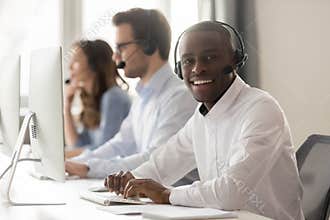 Happy african call center agent in headset posing at workplace