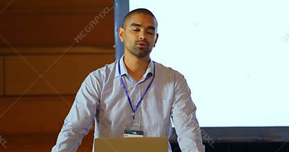 Male speaker with laptop speaking on stage in auditorium 4k