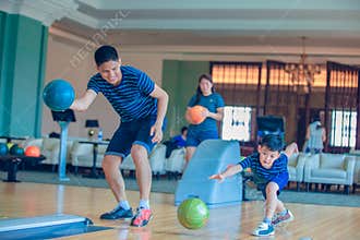 Father teaching son and family play bowling at bowling club on relax time