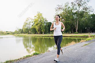 Healthy beautiful young Asian runner woman in sports clothing running and jogging on sidewalk near lake at park in the morning.