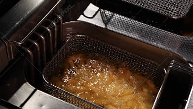 French fries start frying in a wire basket
