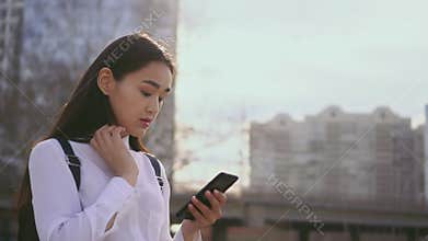 Attractive female using mobile phone in slow motion. Girl straightens her hair.