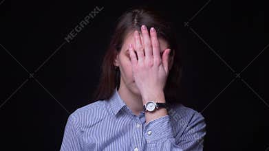 Pretty brunette businesswoman in blue blouse gestures facepalm being annoyed and irritated at black background.
