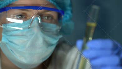 Medical worker holding yellow liquid sample in test tube, analyzing urine in lab
