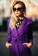Stylish woman in sunglasses posing at camera in sunny day.