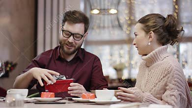 Adult man takes socks out of gift box his wife gave to him and seems unhappy