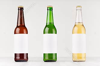 Beer bottles 500ml different colors with blank white label on white wooden board, mock up.