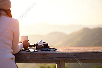 Smiling asian Woman drinking coffee and tea and take a photo and relax in sun sitting outdoor in sunshine light enjoying her warm