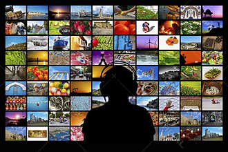 Silhouette of man sitting in front of video wall watching multimedia screens.