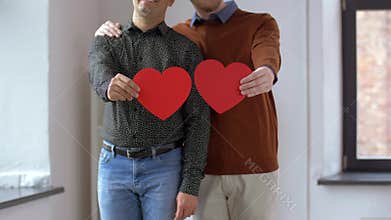 Male gay couple with red heart shapes at home