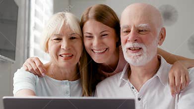 Senior couple and their daughter sitting at home talking via messenger Skype. Smiling laughing